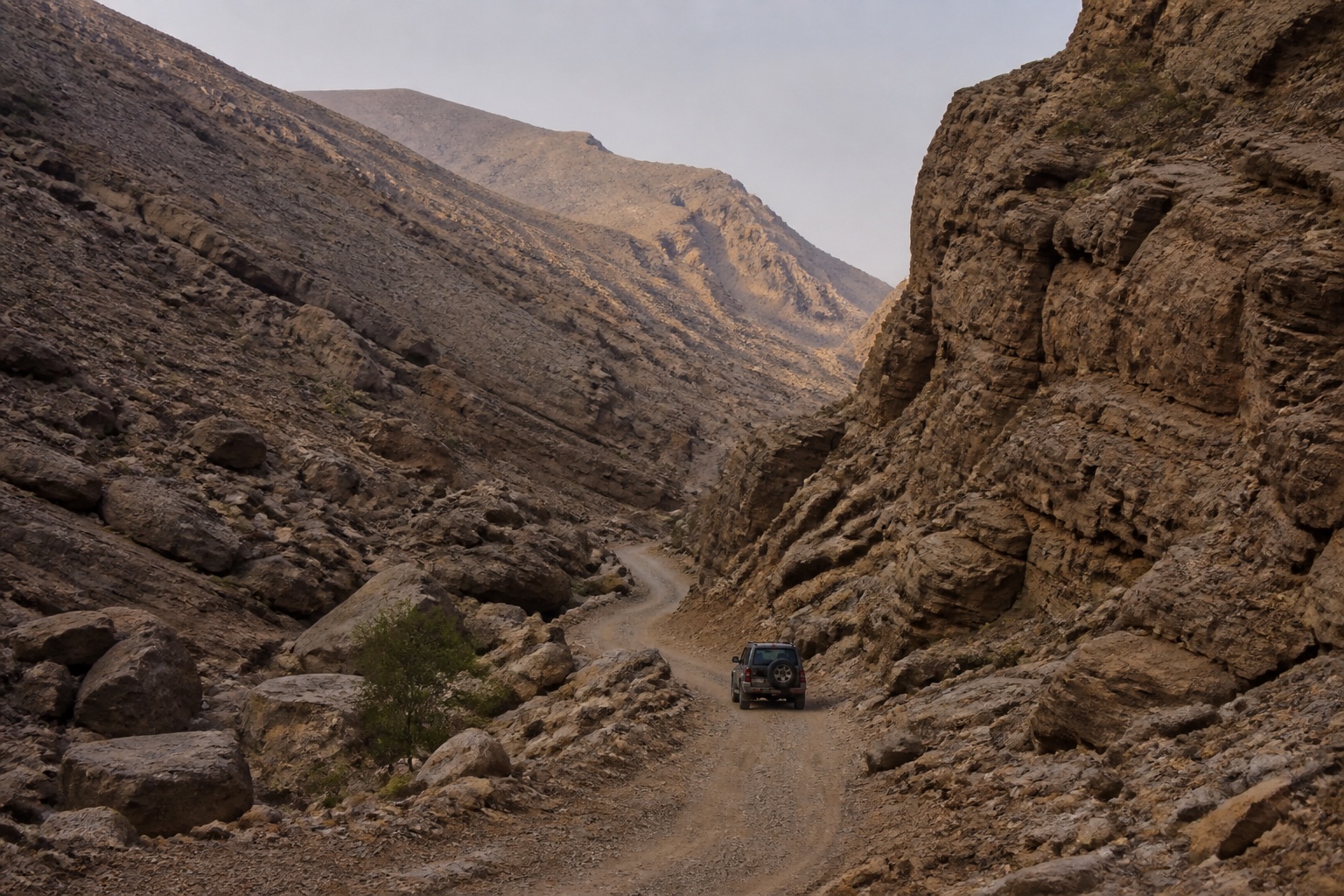 Piste étroite serpentant dans un wadi rocheux d’Oman